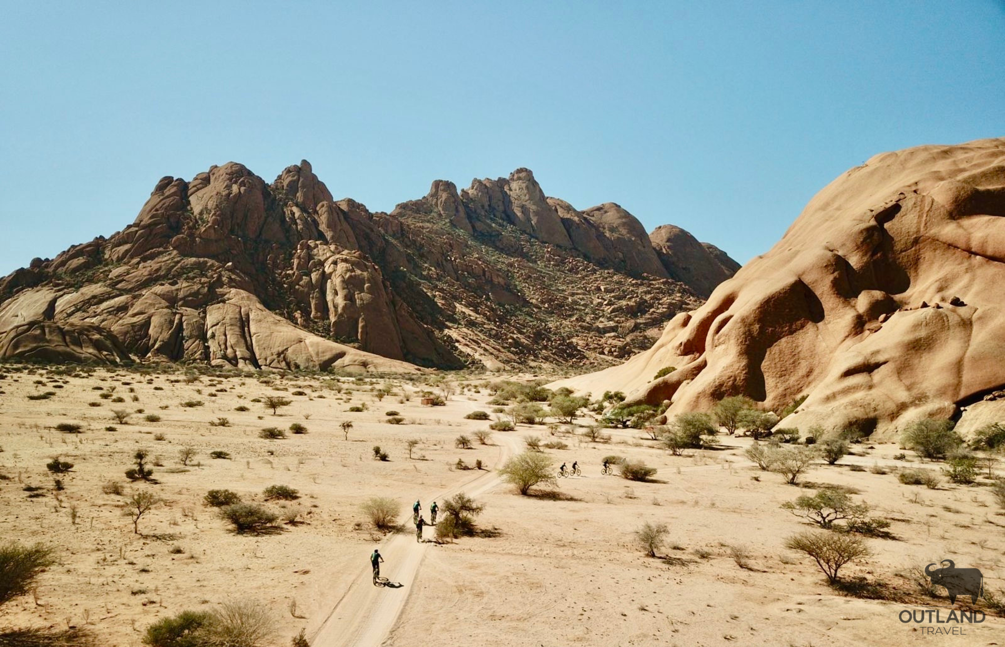 Cyclists riding towards Spitskoppe in Namibia - Outland Travel
