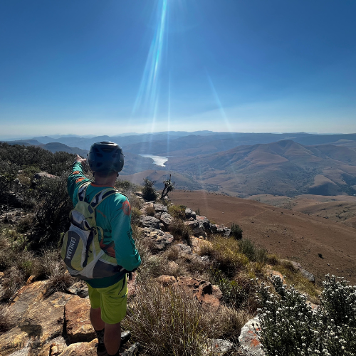 Incredible scenic photo of cyclist overlooking a beautiful valley in South Africa and the dams below in the distance – Outland Travel Incredible scenic photo of cyclist overlooking a beautiful valley in South Africa and the dams below in the distance - Outland Travel
